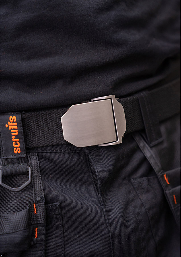 Close-up of a robust Korntex workwear belt with metal buckle on dark-coloured work trousers