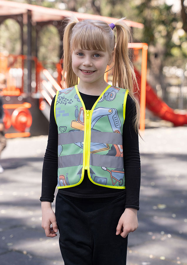 Child in a neon green Korntex safety vest with a construction site pattern on a playground