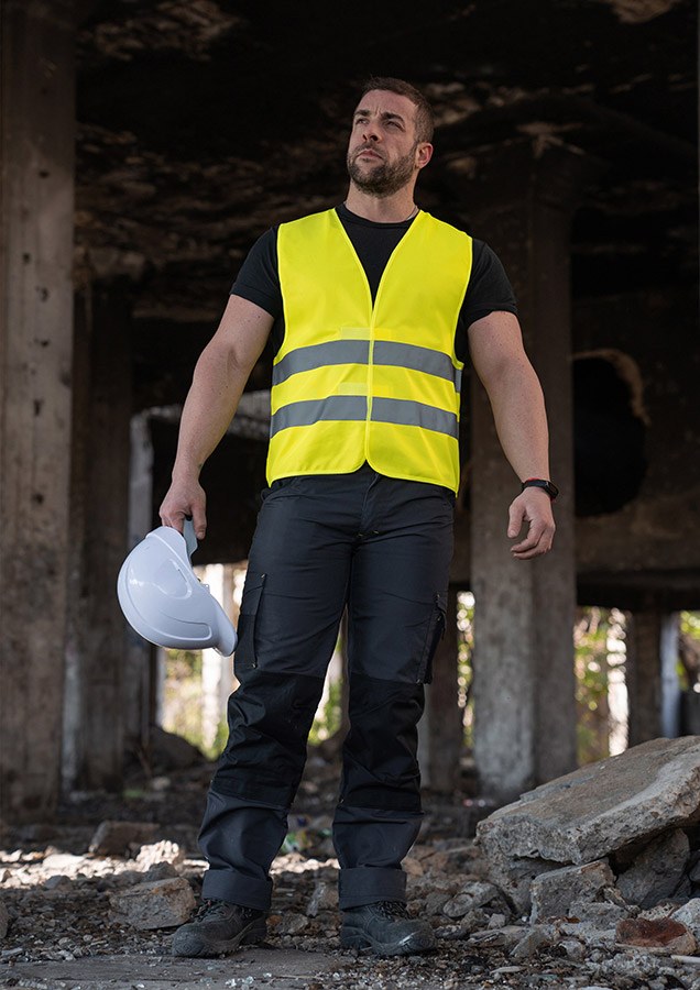 Adult in yellow Korntex safety vest in an industrial environment