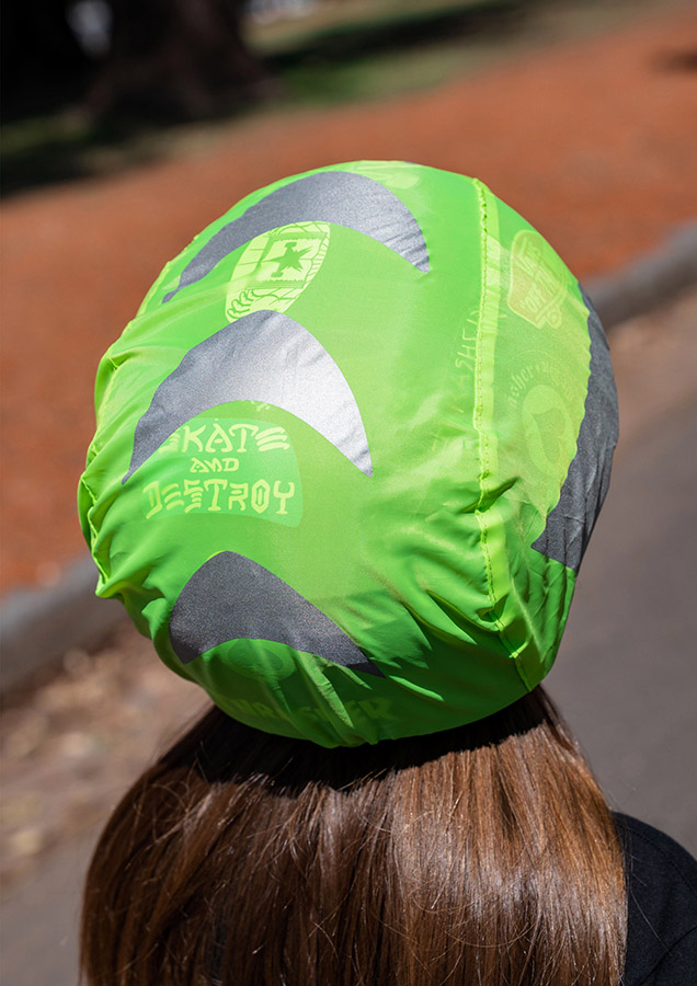 Detailed view of a green Korntex bicycle helmet cover with graphic designs on the head of a young woman