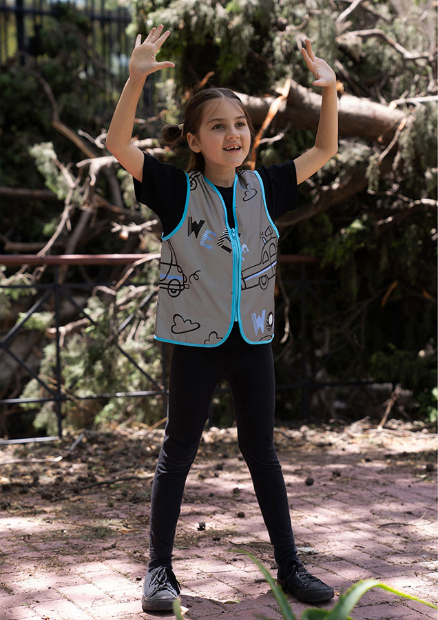 Child in a silver Korntex safety vest with police pattern in a park