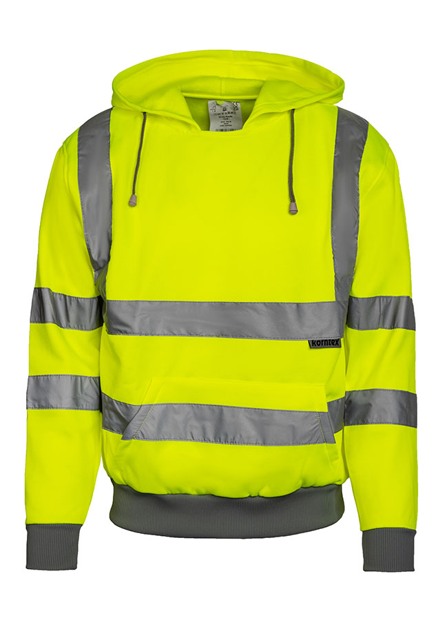 Adult man stands in signal yellow Korntex hi-vis hoodie with reflective stripes and black work trousers in an industrial environment