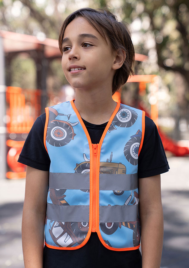 Child in a blue Korntex safety vest with tractor pattern on a playground