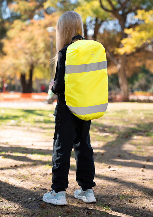 Child wears signal yellow Korntex high-visibility backpack cover with reflectors outdoors