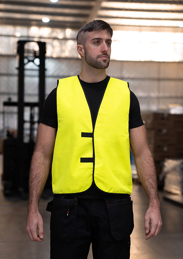 Adult worker in signal yellow Korntex safety vest standing in a warehouse
