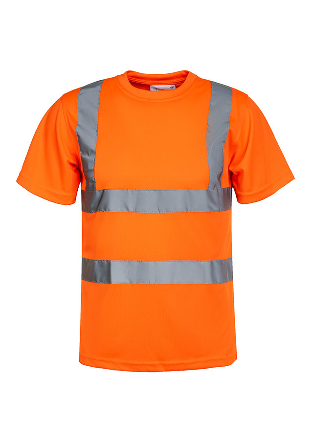 A woman, wearing a signal orange Korntex high-visibility T-shirt and a white hard hat, stands in front of scaffolding at an industrial construction site.