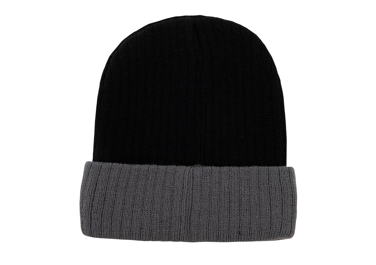An adult wears an embroidered, black and grey Korntex knitted hat in front of a grey wall