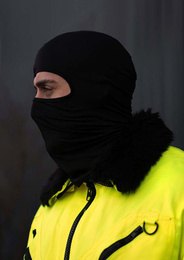 Portrait of an adult man wearing a black Korntex balaclava against a dark background