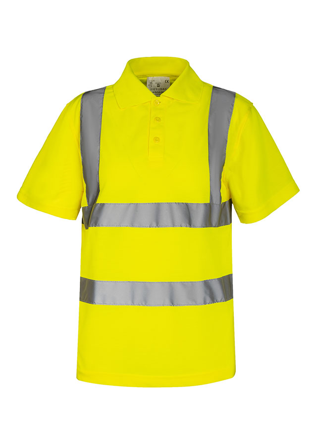 An adult construction worker is standing in front of a demolished building, wearing a fluorescent yellow Korntex polo shirt with a walkie-talkie.