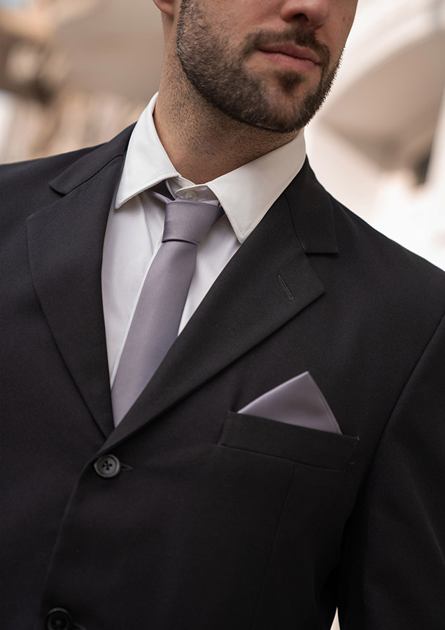 Detailed view of a young businessman in a black suit with a grey tie and a handkerchief