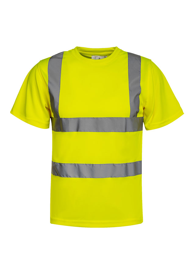 A woman, wearing a signal orange Korntex high-visibility T-shirt and a white hard hat, stands in front of scaffolding at an industrial construction site.
