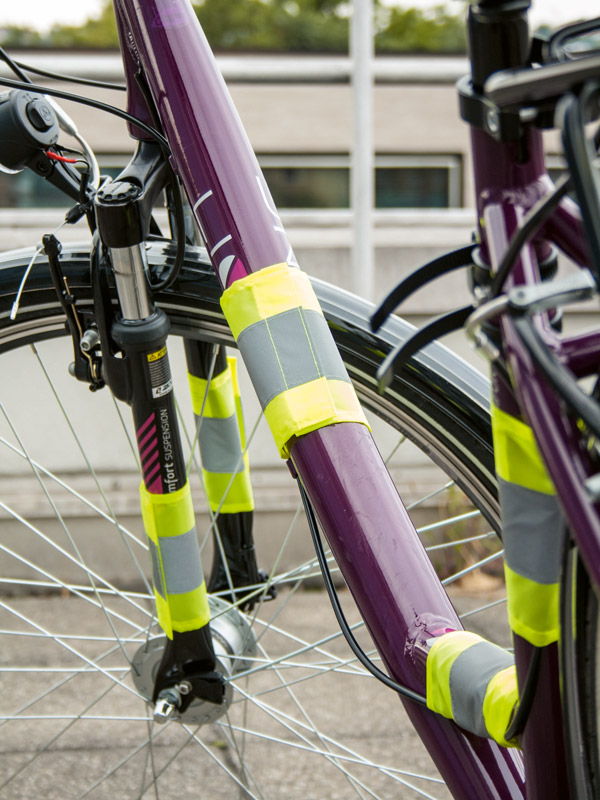 Detailed view of a purple bicycle with yellow Korntex safety reflectors attached to the bicycle frame