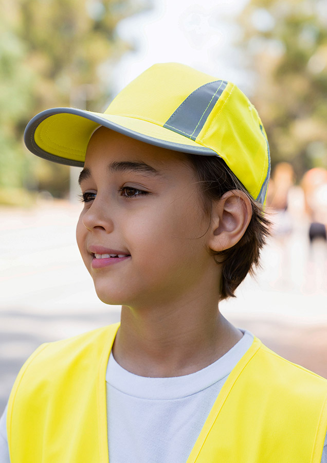 Portrait of a smiling boy with reflective signal yellow Korntex cap in the park