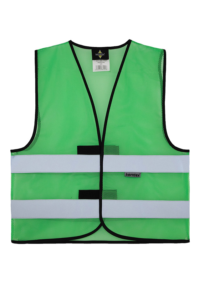 Adult construction worker stands on a building site in a yellow Korntex mesh safety vest and yellow helmet holding tools