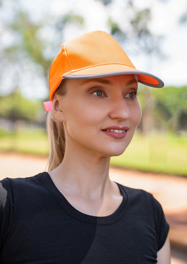 Portrait of an adult smiling woman with reflective orange Korntex cap in the park