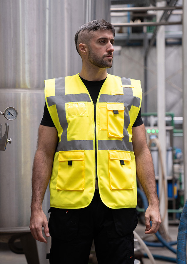 Adult in signal yellow, lined Korntex safety vest with zip fastener in an industrial environment