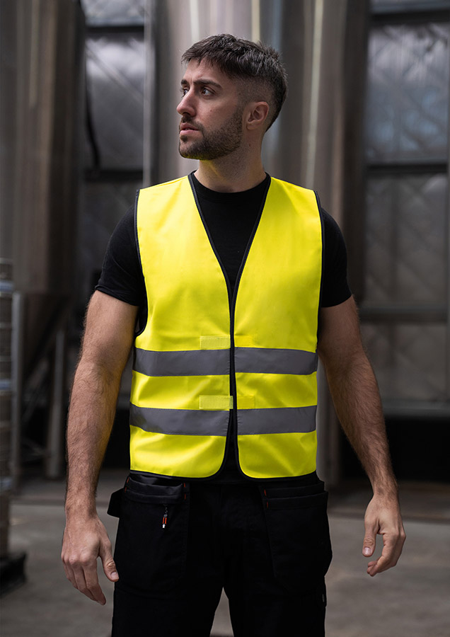 Two adults in fluorescent yellow Korntex safety vests in a factory